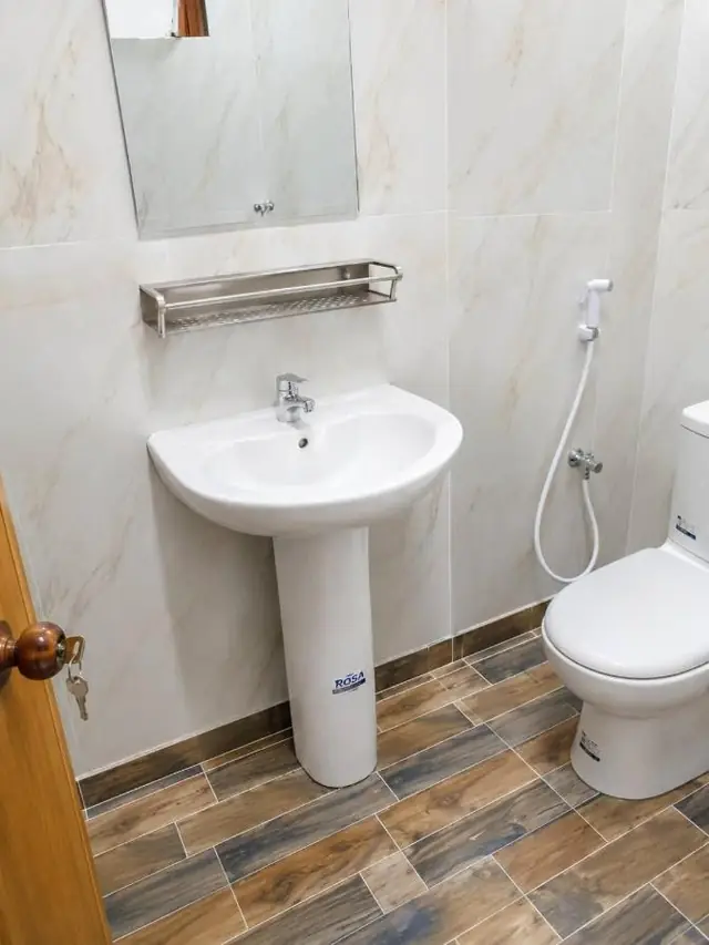 Bathroom with pedestal washbasin, mirror and hand shower