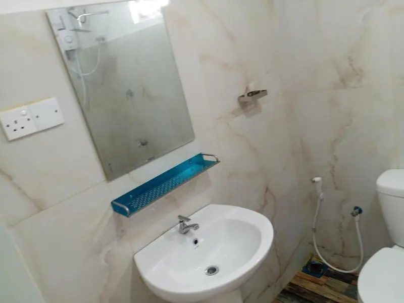 Clean en-suite bathroom with marble-effect tiles, washbasin and mirror