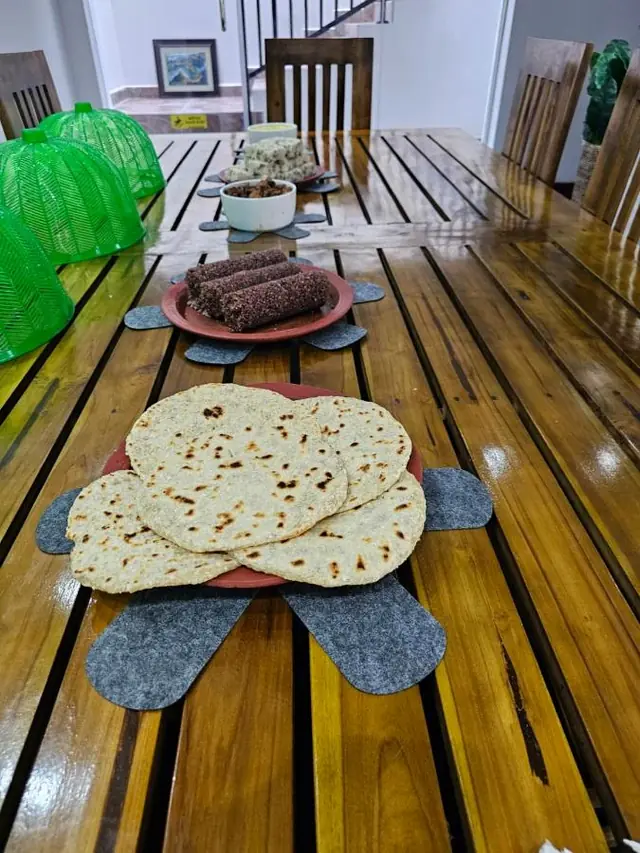 Fresh roti on a woven mat at the wooden breakfast table