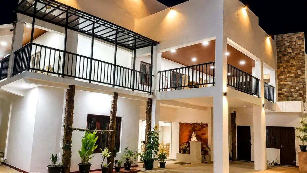 Nil Manel Tourist Resort lit up at night: a modern two-storey building with balconies and a palm-lined garden