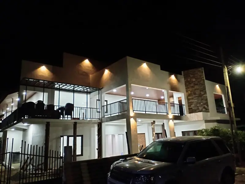 Front of the resort at night with warm lights on both floors and the upstairs terrace