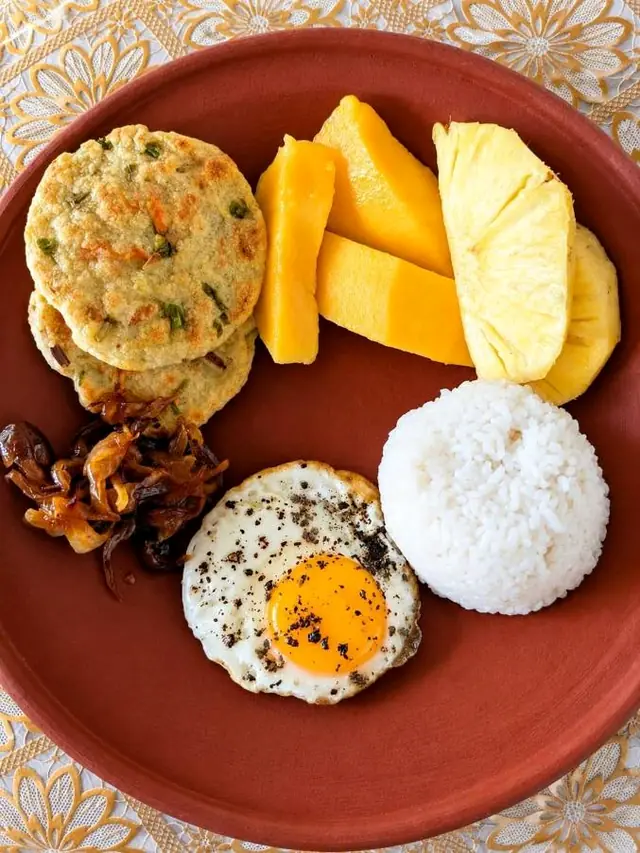 Breakfast plate with egg, fresh fruit, rice and fried snacks