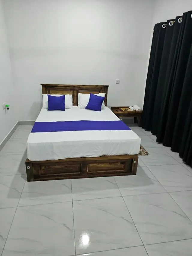 Simple double room with a violet runner and wooden bed frame