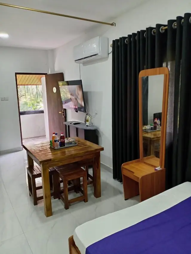 Corner of a room with a wooden writing desk, mirror and window to the garden