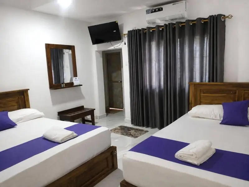Air-conditioned room with two beds, dark curtains, mirror and TV