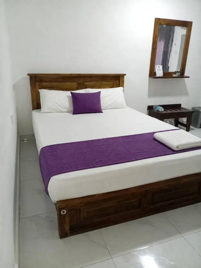 Double room with a violet bed runner, wooden bedside table and mirror