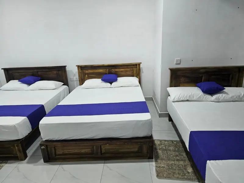 Spacious family room with three beds in a row, wooden bed frames and white linen