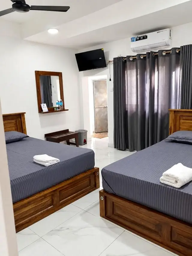 Room with two beds in grey linen, air conditioning and an en-suite door