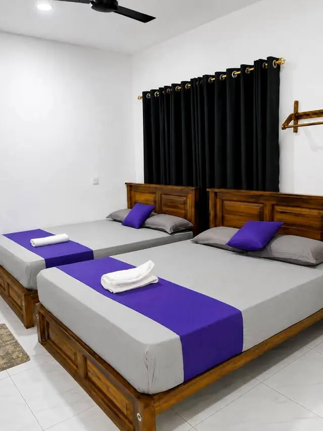 Room with two large beds side by side under a window with dark curtains