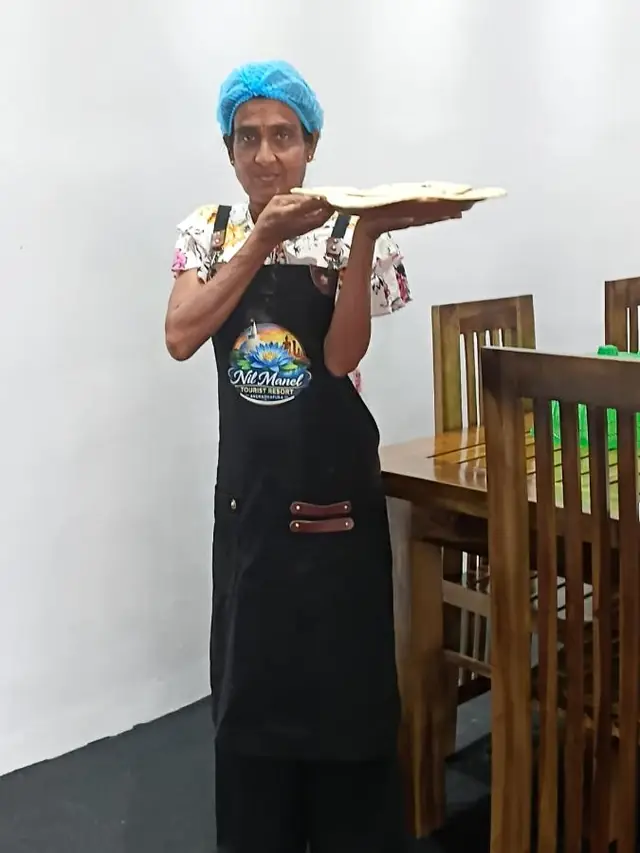 A member of the Nil Manel kitchen team holding a plate of fresh roti