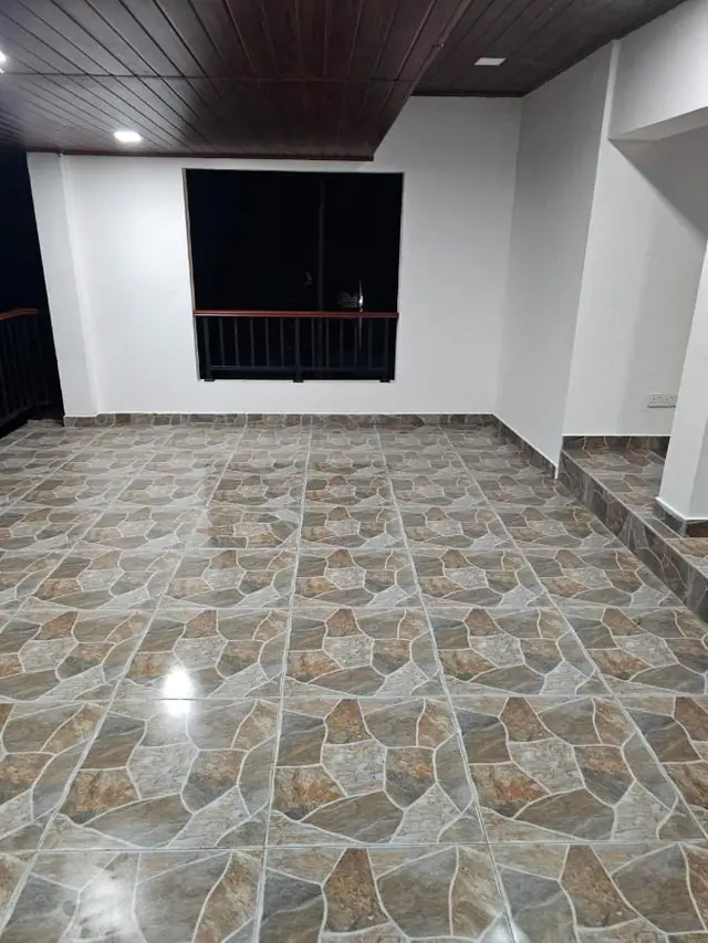 Upstairs open hall with patterned tiles and a wooden ceiling, opening onto the balcony